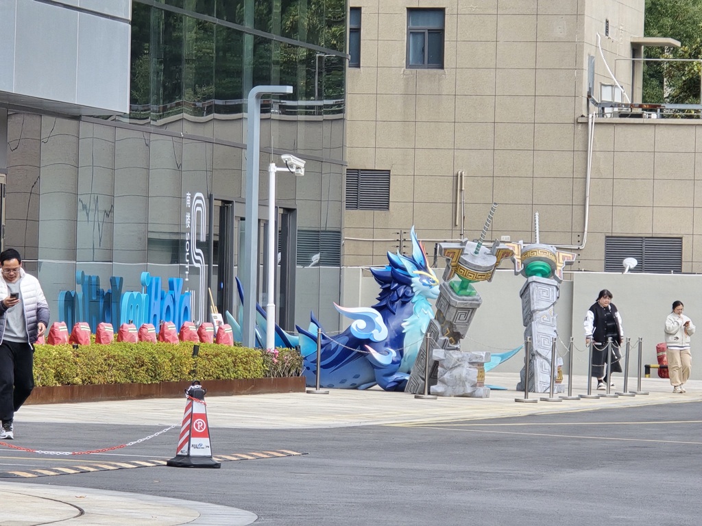 正面入口と思われる広場に miHoYo ロゴと山隠れの猊獣のオブジェが置かれている写真